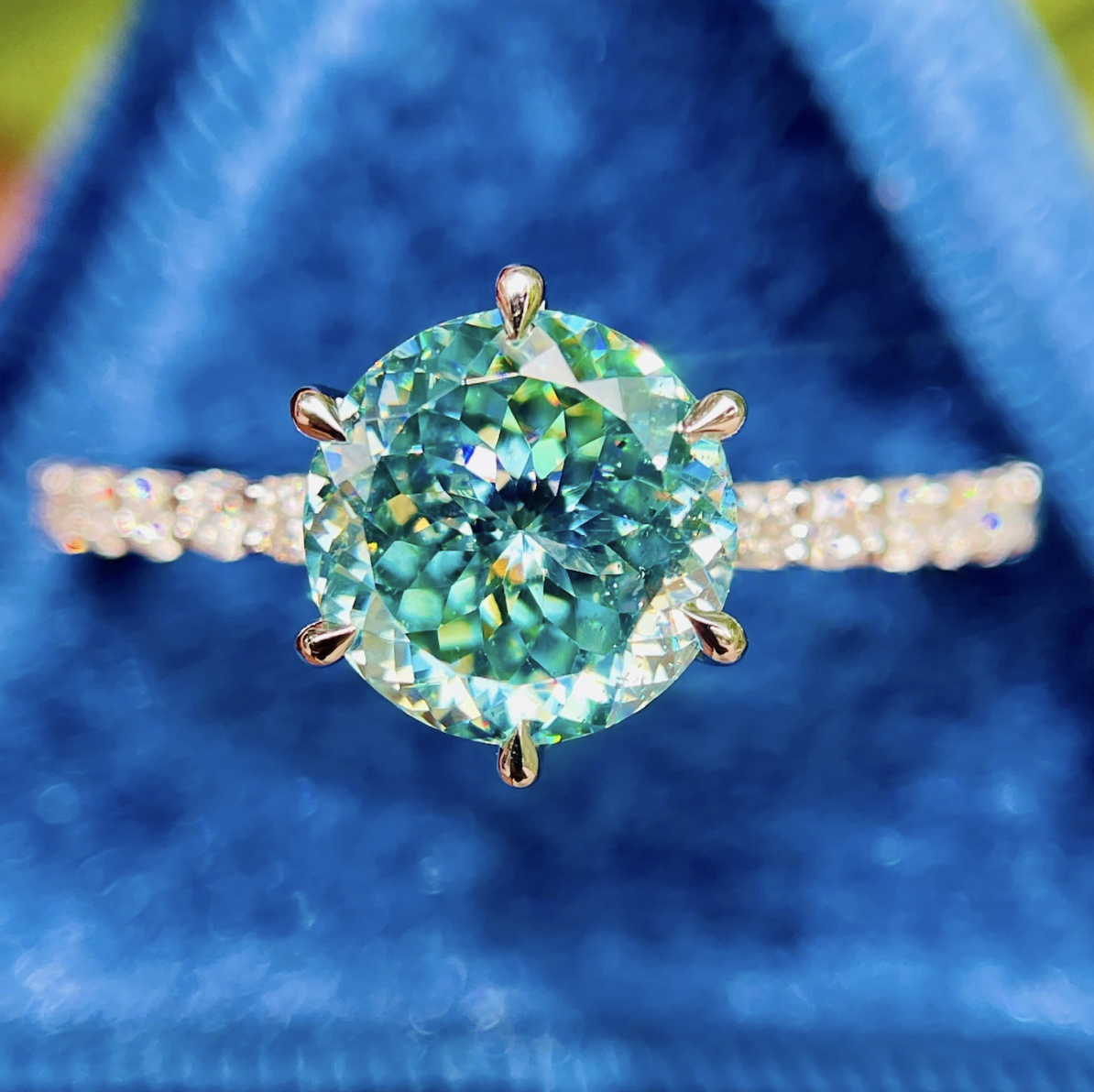 Ring with a green gemstone and gold setting on a blue fabric background