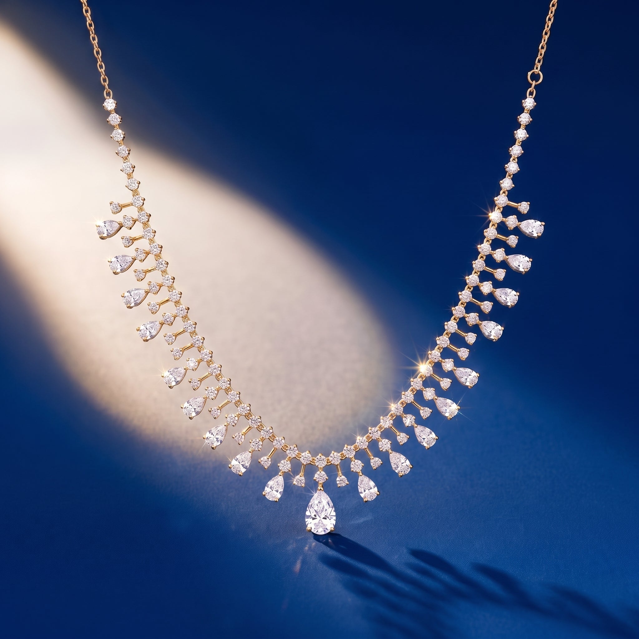 Gold tennis necklace with pear drop on royal blue